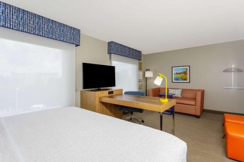 a hotel room with a bed and a desk with a television at Hampton Inn & Suites Tallahassee I-10-Thomasville Road in Tallahassee