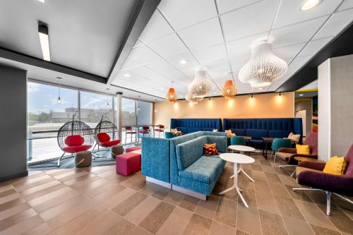 a lobby with a blue couch and chairs and tables at Tru by Hilton Plano Hwy 75 in Plano