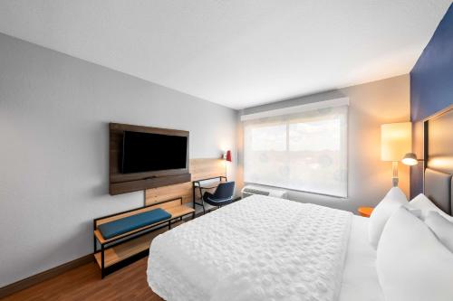 a hotel room with a bed and a flat screen tv at Tru by Hilton Plano Hwy 75 in Plano