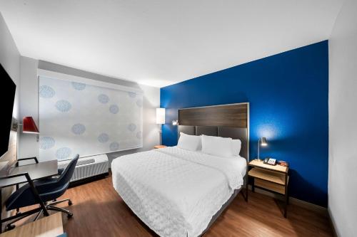 a hotel room with a white bed and a blue wall at Tru by Hilton Plano Hwy 75 in Plano