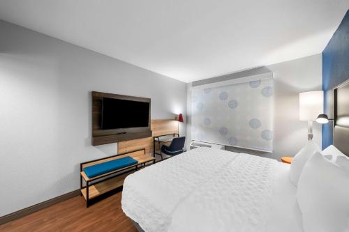 a hotel room with a bed and a flat screen tv at Tru by Hilton Plano Hwy 75 in Plano