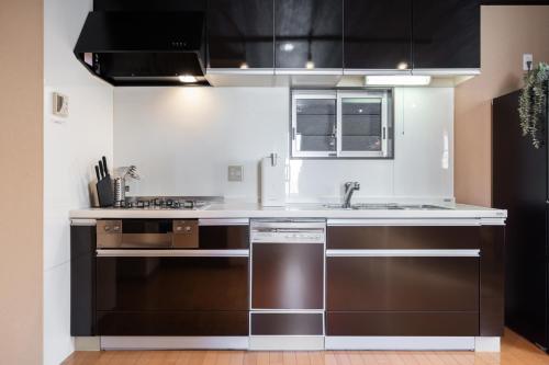 a kitchen with stainless steel appliances and black cabinets at Muji Arashiyama Villa 無時嵐1階2階賃貸し 駅まで徒歩2分 in Kyoto