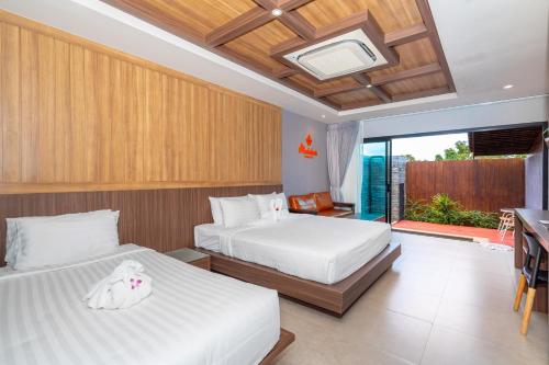 a bedroom with two beds and a balcony at Malabar Pool Villa Phuket in Phuket Town