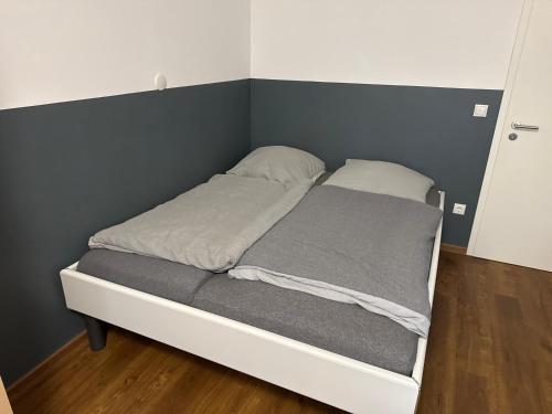 a small bed in a room with a gray wall at Pension Haus Erika in Lingen
