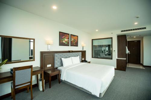 a bedroom with a large white bed and a desk at Peace Hotel Hạ Long in Ha Long