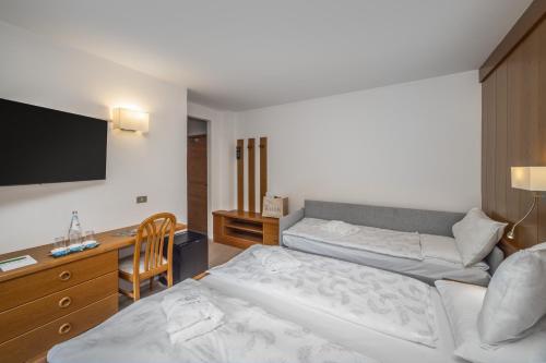 a hotel room with two beds and a flat screen tv at Hotel Ramon in Campitello di Fassa