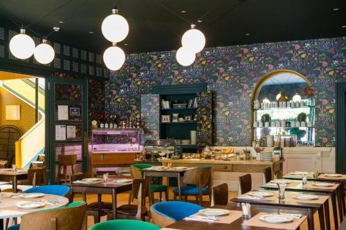 un restaurant avec des tables et des chaises et un mur fleuri dans l'établissement Grand Hotel De La Poste - Lyon Sud - Vienne, à Vienne