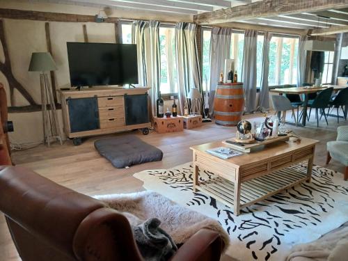 a living room with a tv and a couch and a table at Bergerie en forêt in Allons