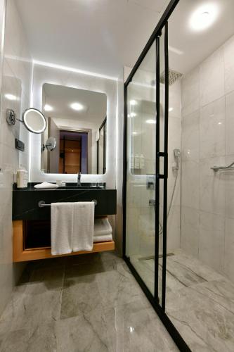 a bathroom with a shower and a sink and a mirror at Radisson Hotel Mersin in Mersin
