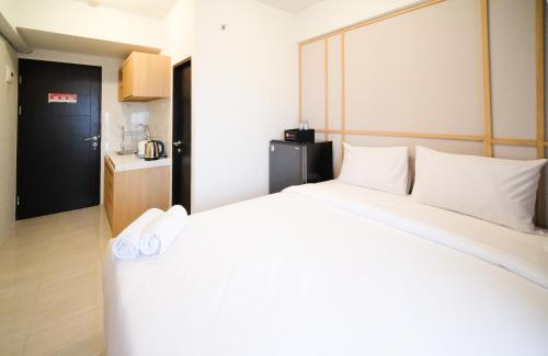 a bedroom with a large bed with white pillows at Best Choice and Strategic Location Studio at Apartment Suncity Residence By Travelio in Sidoarjo