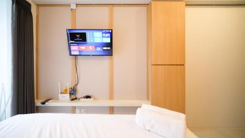 a bedroom with a bed and a tv on a wall at Best Choice and Strategic Location Studio at Apartment Suncity Residence By Travelio in Sidoarjo