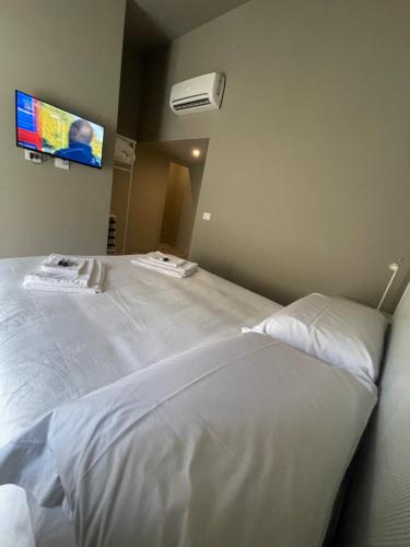 a bedroom with a white bed with a tv on the wall at Moronero in Ragusa