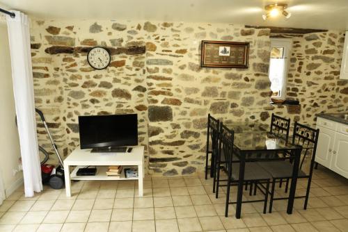 salon z telewizorem i stołem z krzesłami w obiekcie Maisonnette et gîte proches de la mer w mieście Plouha