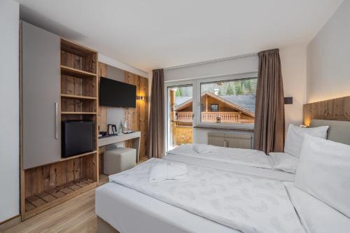 a bedroom with a large bed and a large window at Hotel Ramon in Campitello di Fassa