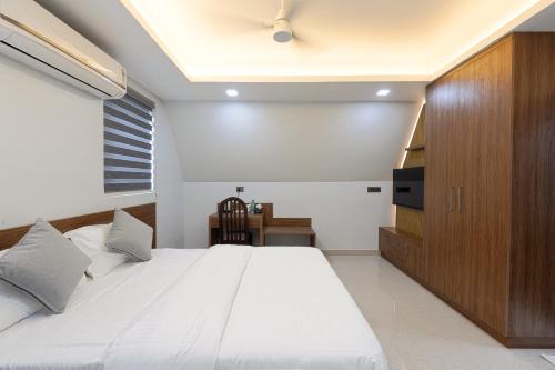 a bedroom with a large white bed and a television at EVE Nest in Edappally