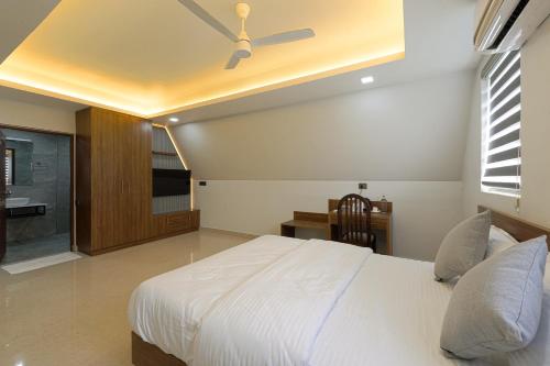 a bedroom with a white bed with a ceiling fan at EVE Nest in Edappally