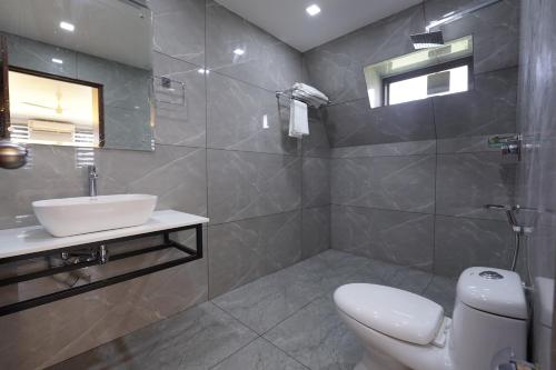 a bathroom with a toilet and a sink and a mirror at EVE Nest in Edappally