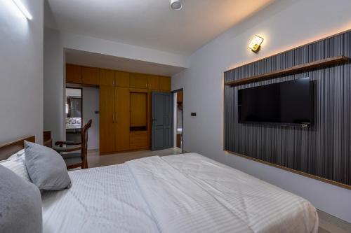 a bedroom with a large bed and a flat screen tv at EVE Nest in Edappally