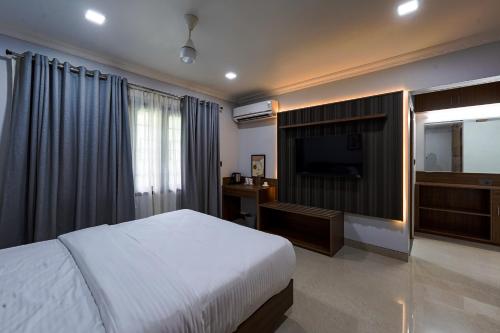 a bedroom with a bed and a flat screen tv at EVE Nest in Edappally