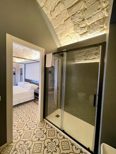 a bathroom with a glass shower and a bedroom at Moronero in Ragusa
