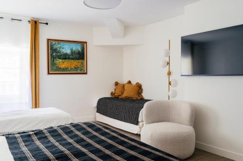 a bedroom with a bed and a chair and a television at Domaine La Gentilhommière in Satillieu