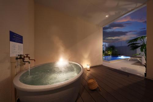 a bathroom with a tub with a view of a pool at クリスタルヴィラ白良浜ビーチ in Kanayama