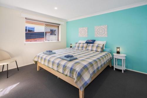 a bedroom with a bed with a blue wall at Sasta Nambucca in Nambucca Heads