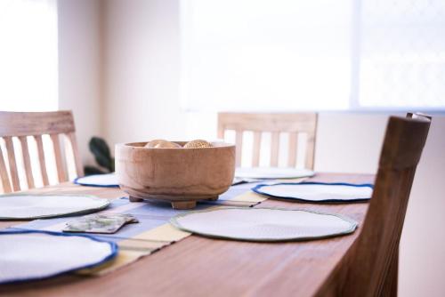 a wooden table with plates and a bowl on it at Sasta Nambucca in Nambucca Heads