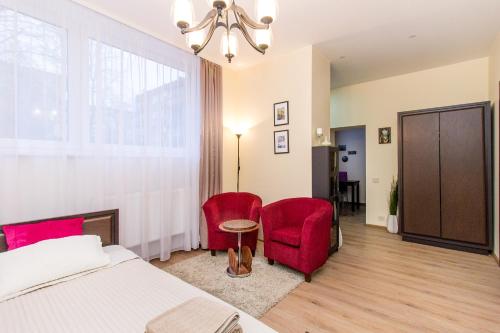 1 dormitorio con 1 cama y 2 sillas rojas en Apartamentai 555, en Vilna