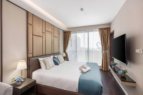 a bedroom with a large bed and a television at 1BDR apartment with private terrace with jacuzzi and sea view by My Home Phuket in Ban Lum Fuang