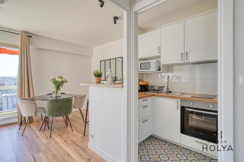 une cuisine avec des armoires blanches et une table avec des chaises dans l'établissement Le Panoramique- Vue Tour Eiffel - 313B, à Paris