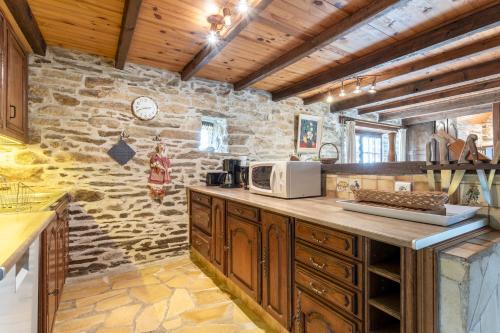- une cuisine avec des placards en bois et un mur en pierre dans l'établissement Chaumière Ty Plouz, à Plovan
