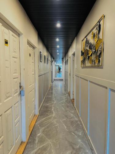 a hallway with white doors and a painting on the wall at Hotel Royal Palm Inn in Faizābād