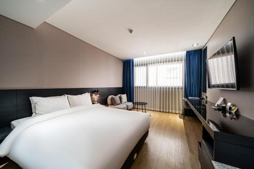 a bedroom with a large white bed and a chair at Rivertain Hotel Gyeongju in Gyeongju