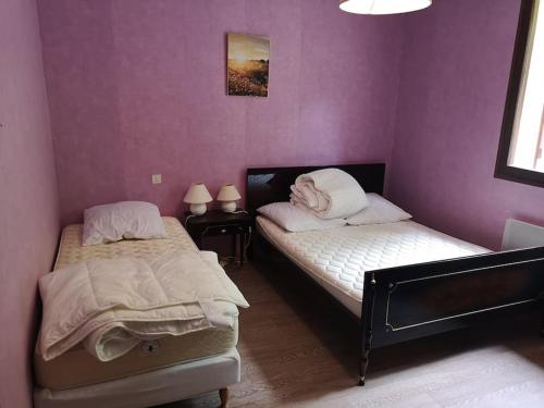 two beds in a bedroom with purple walls at Charmant gîte de montagne avec cheminée in Saint-Paul-de-Salers