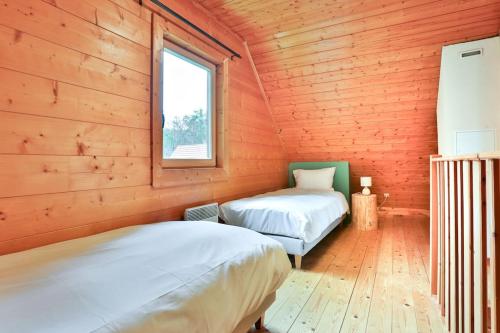 two beds in a wooden room with a window at Domaine la Clairière et Bain nordique in Soultzmatt