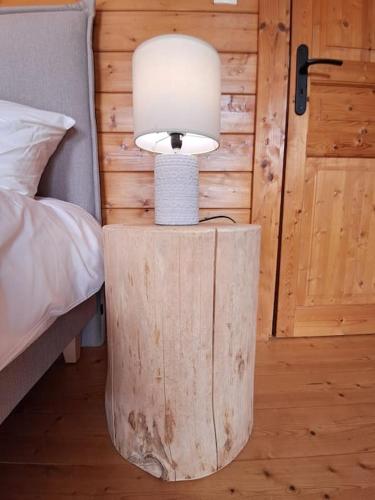 a lamp on a wooden table next to a bed at Domaine la Clairière et Bain nordique in Soultzmatt