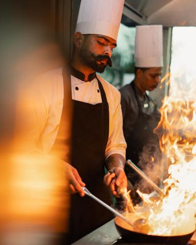 two chefs cooking in a wok in a kitchen at Hyatt Place Pune Hinjawadi in Pune