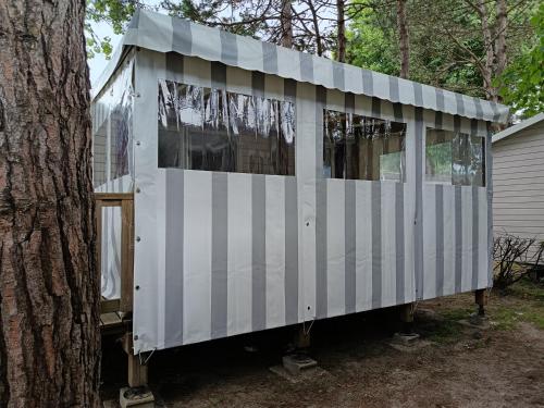 a white house is sitting next to a tree at MH F52 Camping Bois Masson in Saint-Jean-de-Monts