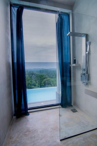 a bathroom with a glass shower door with a view at NAKED Villa in Dodampe