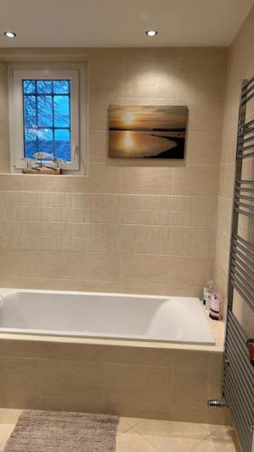 La salle de bains est pourvue d'une baignoire blanche et d'une fenêtre. dans l'établissement Spacious 1st floor apartment with panoramic views, à Lisle