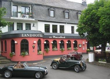 deux vieilles voitures garées devant un bâtiment dans l'établissement Landhotel am Wenzelbach, à Prüm