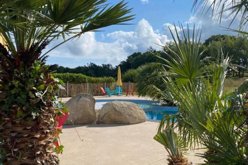 - une piscine avec des palmiers et des rochers dans l'établissement Le Domaine De Mesqueau, à Plougasnou