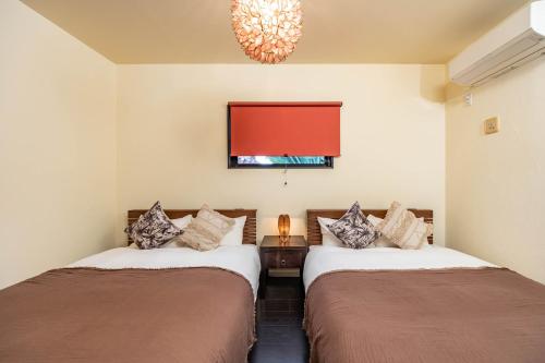 two beds in a room with a red window at 1688House美ら海 in Motobu