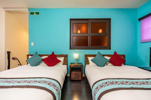 two beds in a room with blue walls at 1688House美ら海 in Motobu