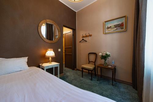 a bedroom with a bed and a mirror and a chair at Boutique Hotel Virkas muiža in Kuldīga