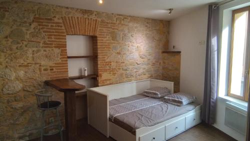 une chambre avec un lit et un mur de briques dans l'établissement studio centre Lavaur, à Lavaur