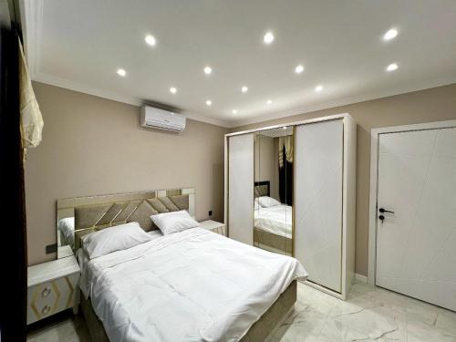 Un dormitorio con una gran cama blanca y un espejo. en 4 bedroom, 5 bathroom triangle, en Gabala