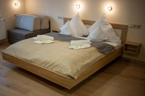 a bedroom with a bed with two pillows and a chair at Holiday Apartmanház Gyula in Gyula