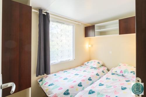 une petite chambre avec un lit et une fenêtre dans l'établissement Mobilhome au rythme des Îles Sérénité & Nature, à Bias